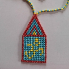 Inmate Kalki dasa—from California—crafted this beautiful necklace: it is made with plain paper. Each “bead” is a long paper strip cut thinly, then painstakingly rolled up on a paperclip. It is then glued, covered with floor wax and strung up together and expertly arranged to form an OM symbol.