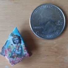 Inmate Leland D.—from California—picks small rocks in the prison yard and use floor wax to glue small pictures of Kṛṣṇa on them. You can compare their size with the quarter next to them.